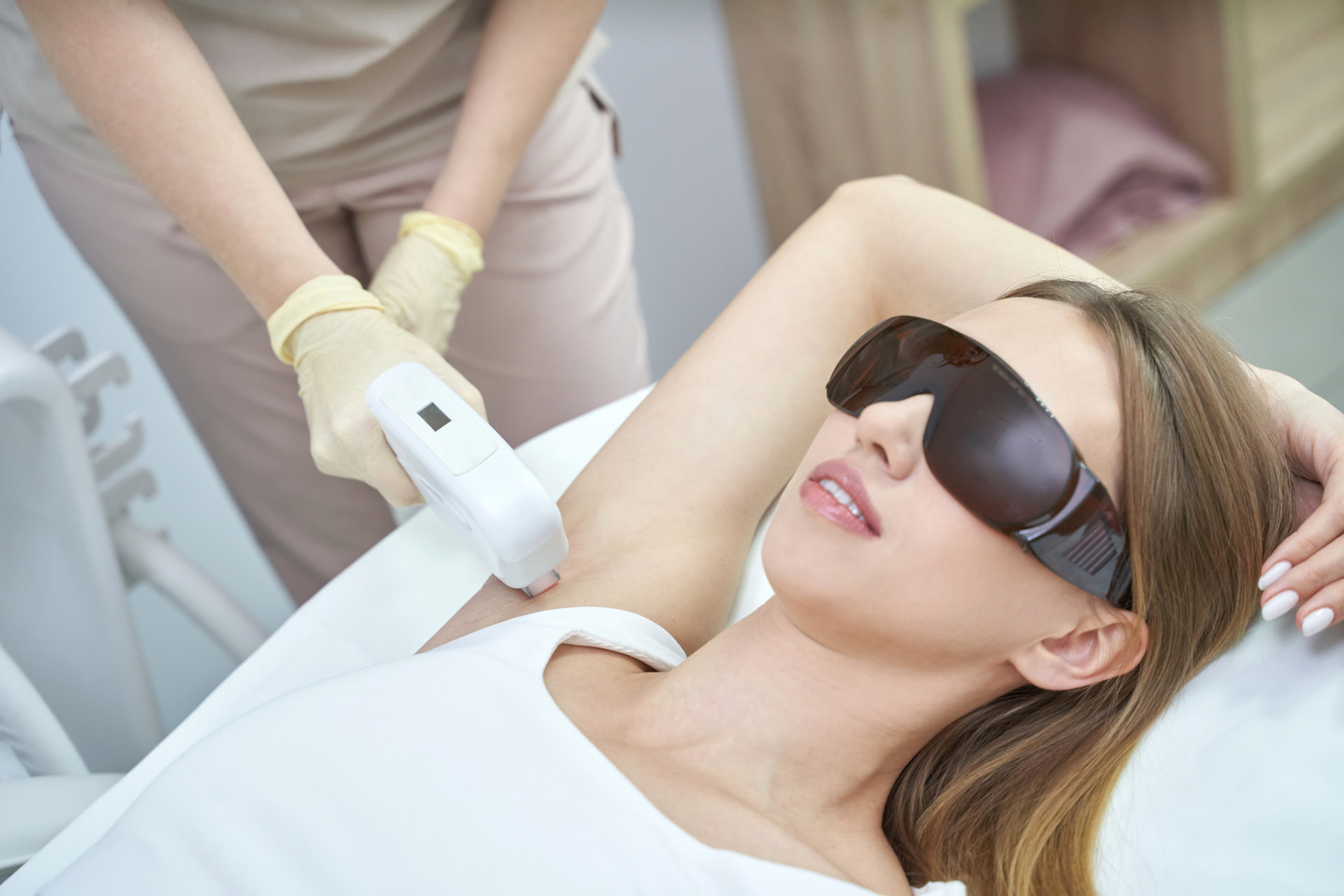 Kundin mit Schutzbrille erhält eine Diodenlaser-Behandlung an der Achsel